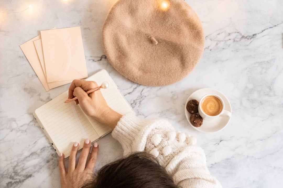 A person writing in a journal beside a cup of coffee, warm morning light